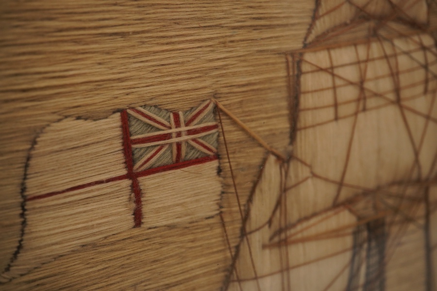 A maple framed 19th century ‘woolie’ folk art, wool work embroidery of a fully rigged sailing ship. Embroidered by a sailor using wading, creating raised stump work sails, using long straight stem stitches both verticall